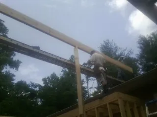 Carpenter setting a ridge beam over a new addition frame — Ice Dam Removal by Roofing Brothers in Welton