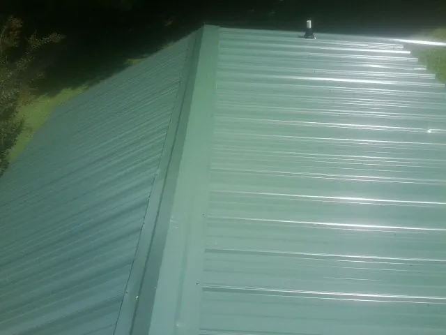 New green metal panels meeting at the ridge of a roof — Flat Roof Repair work by our crew in Welton