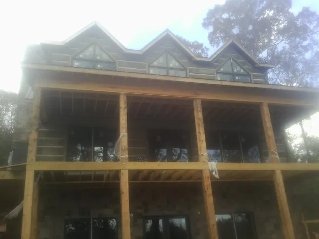 Dormers and porch framing on a large log home under construction — Roof Coating work by our crew in Welton