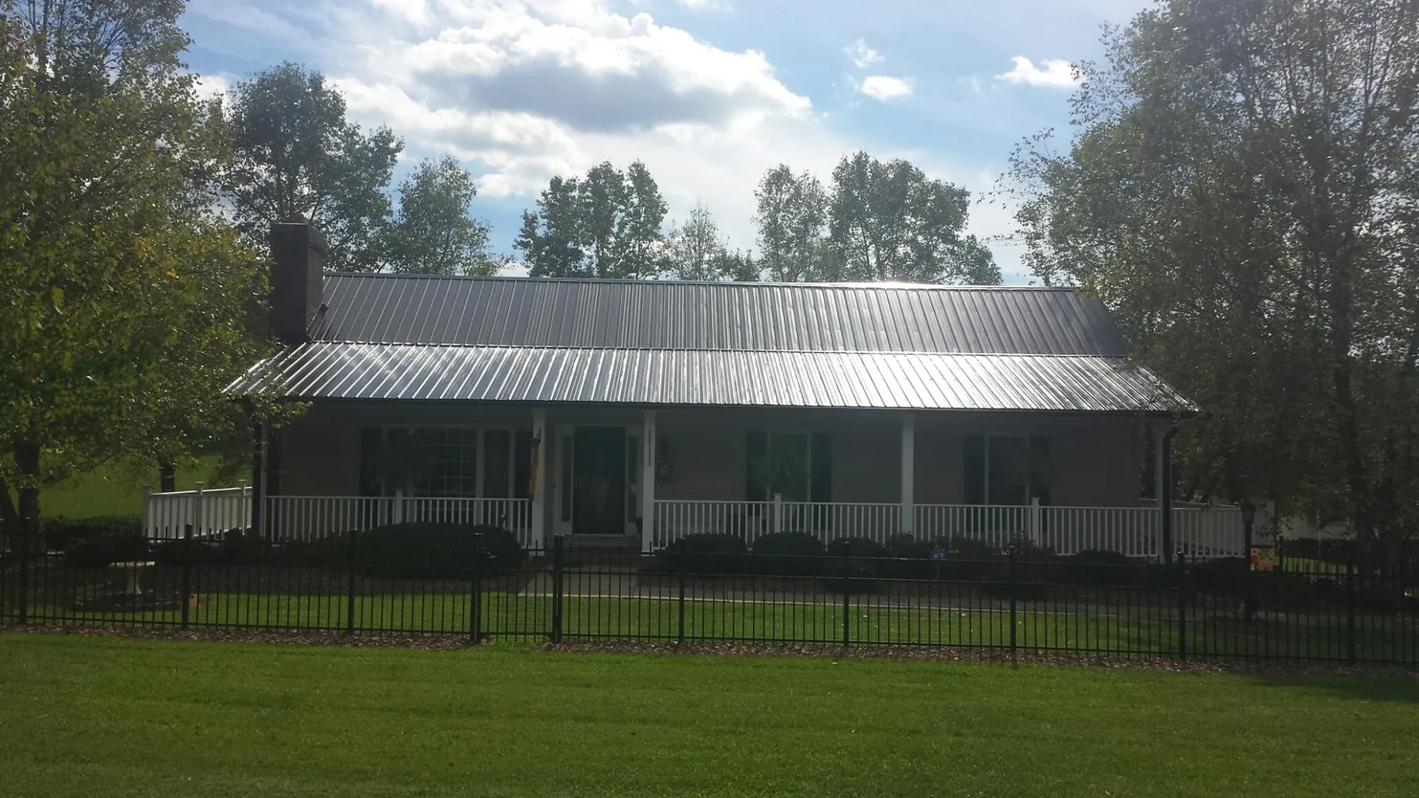 Gray metal roof on a brick ranch with a full width front porch — Gutter Guard Installation work by our crew in Welton