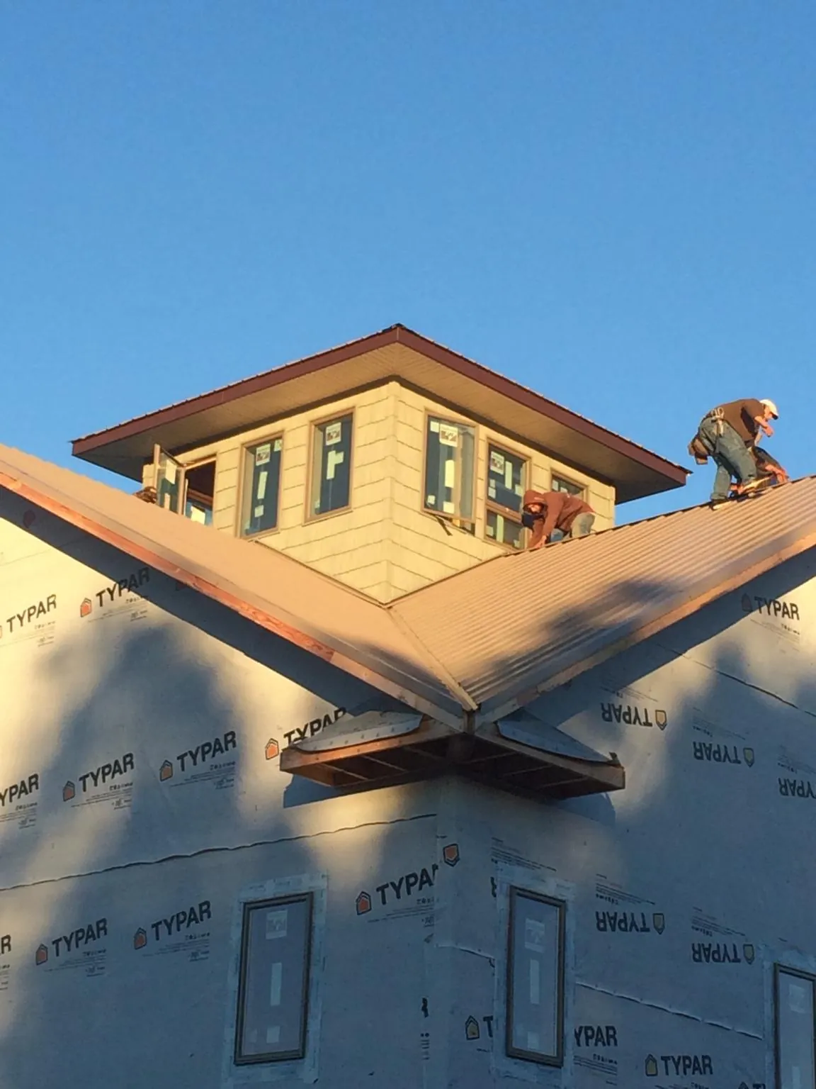 Roofers working around a rooftop cupola on a new metal roof at sunset — Roof Waterproofing in Welton by Roofing Brothers